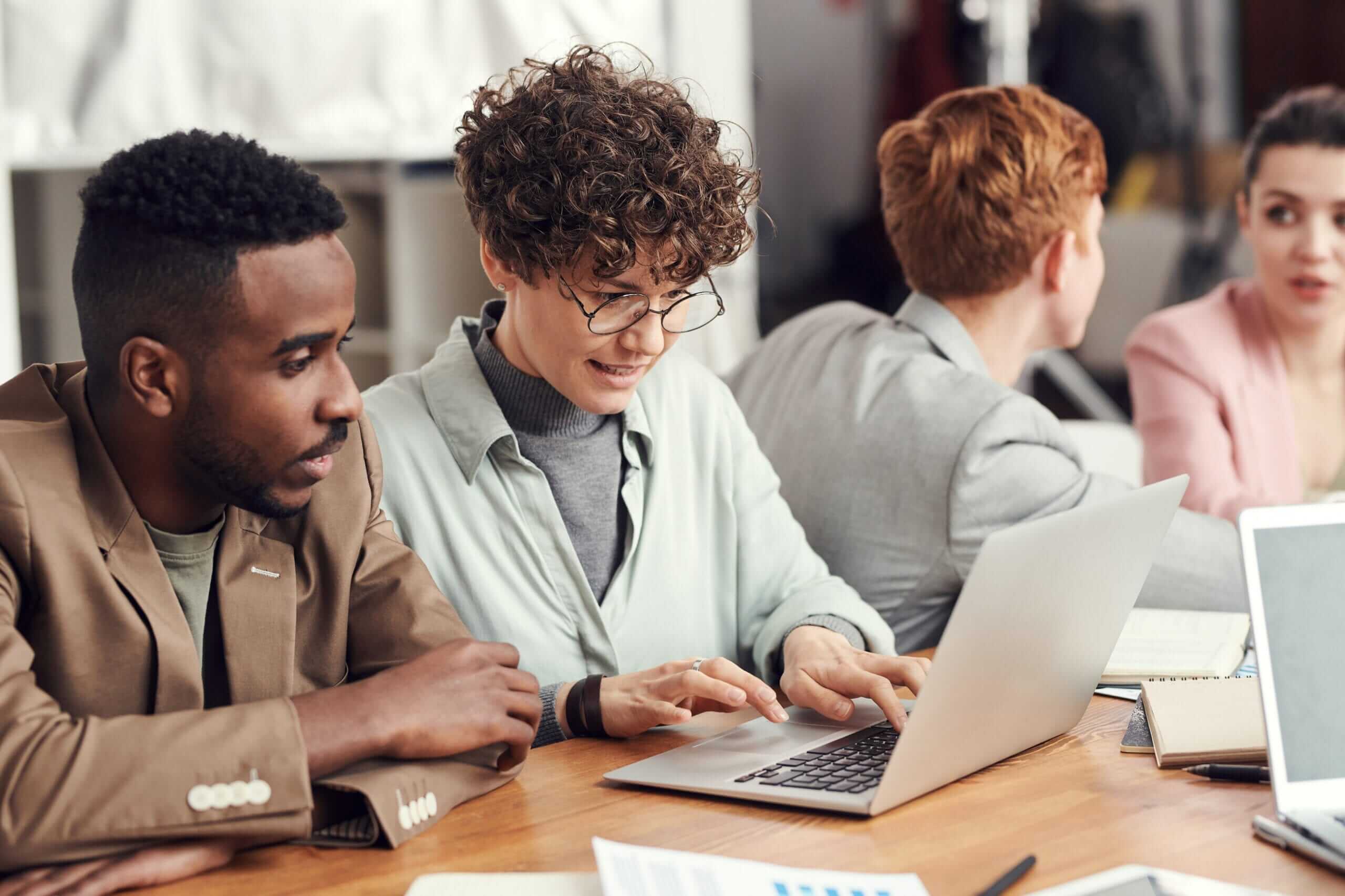 compliance empresarial - um homem e uma mulher olhando para o notebook que está aberto sobre a mesa